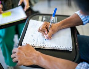 close up of college student doing math work in a spiral notebook